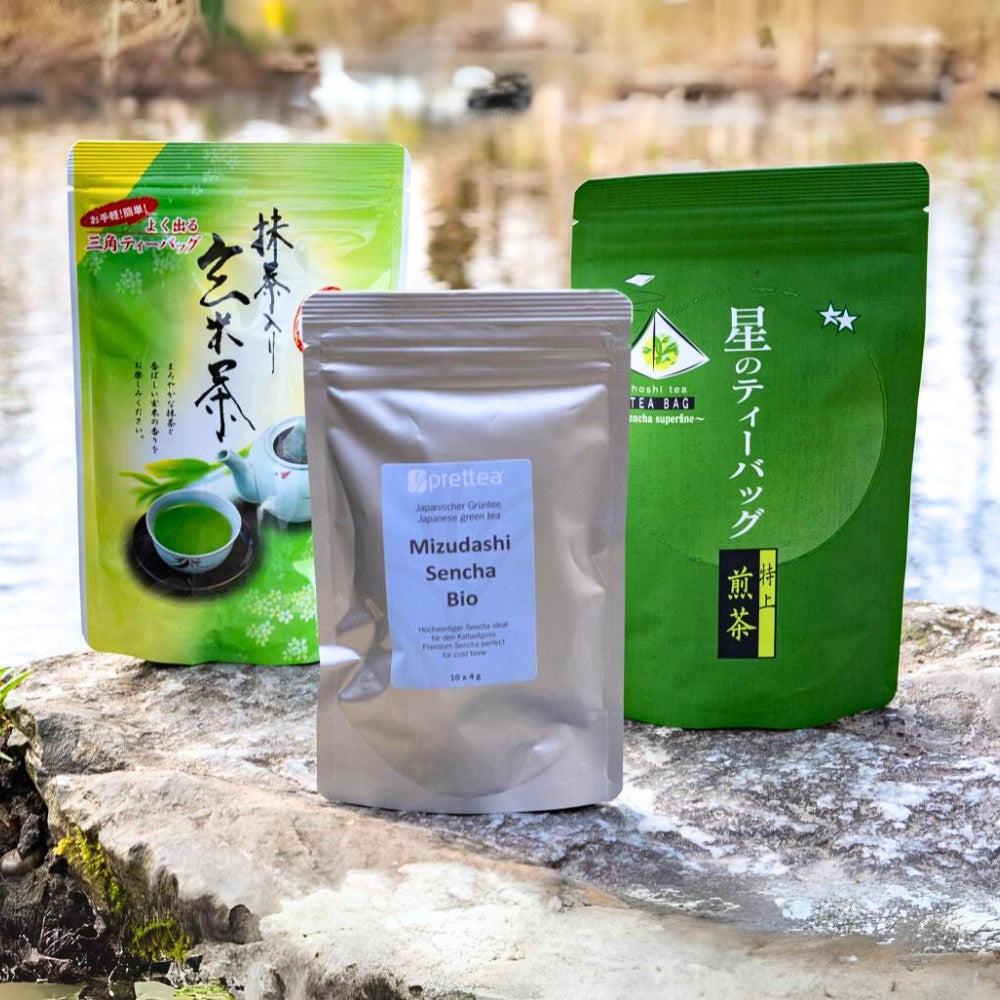 3 japanische Mizudashi Teebeutel Verpackungen auf einem Stein nebeneinander gestellt vor einem Fluss.